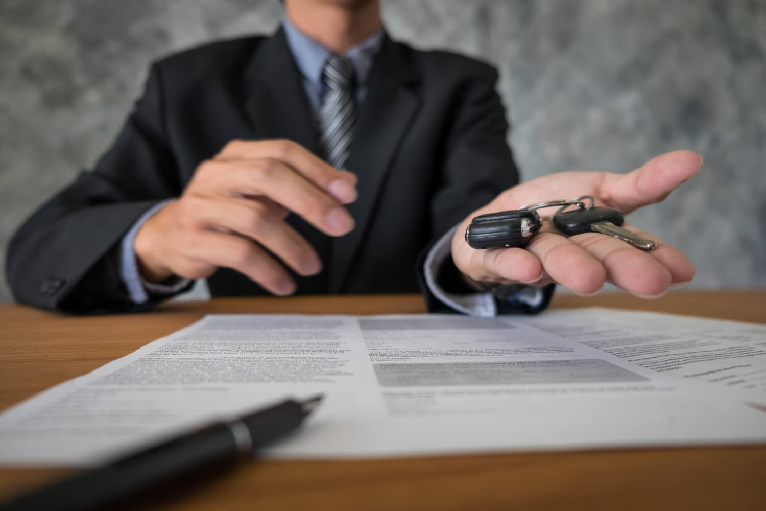 Consulente consegna le chiavi dell’auto durante la firma del contratto, rappresentando i rischi e le truffe nel noleggio a lungo termine.
