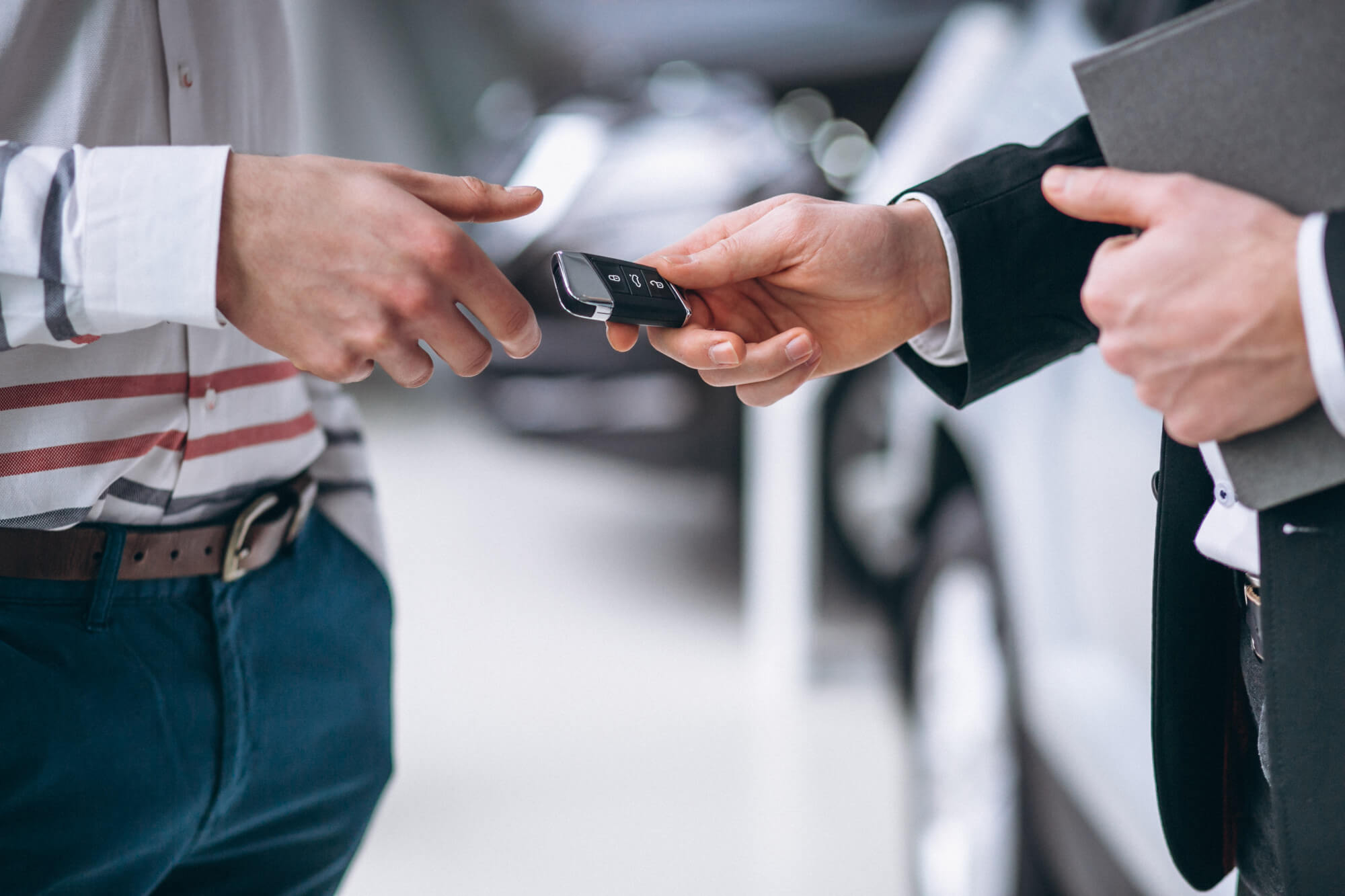Due uomini in giacca e cravatta si scambiano una chiave d'auto