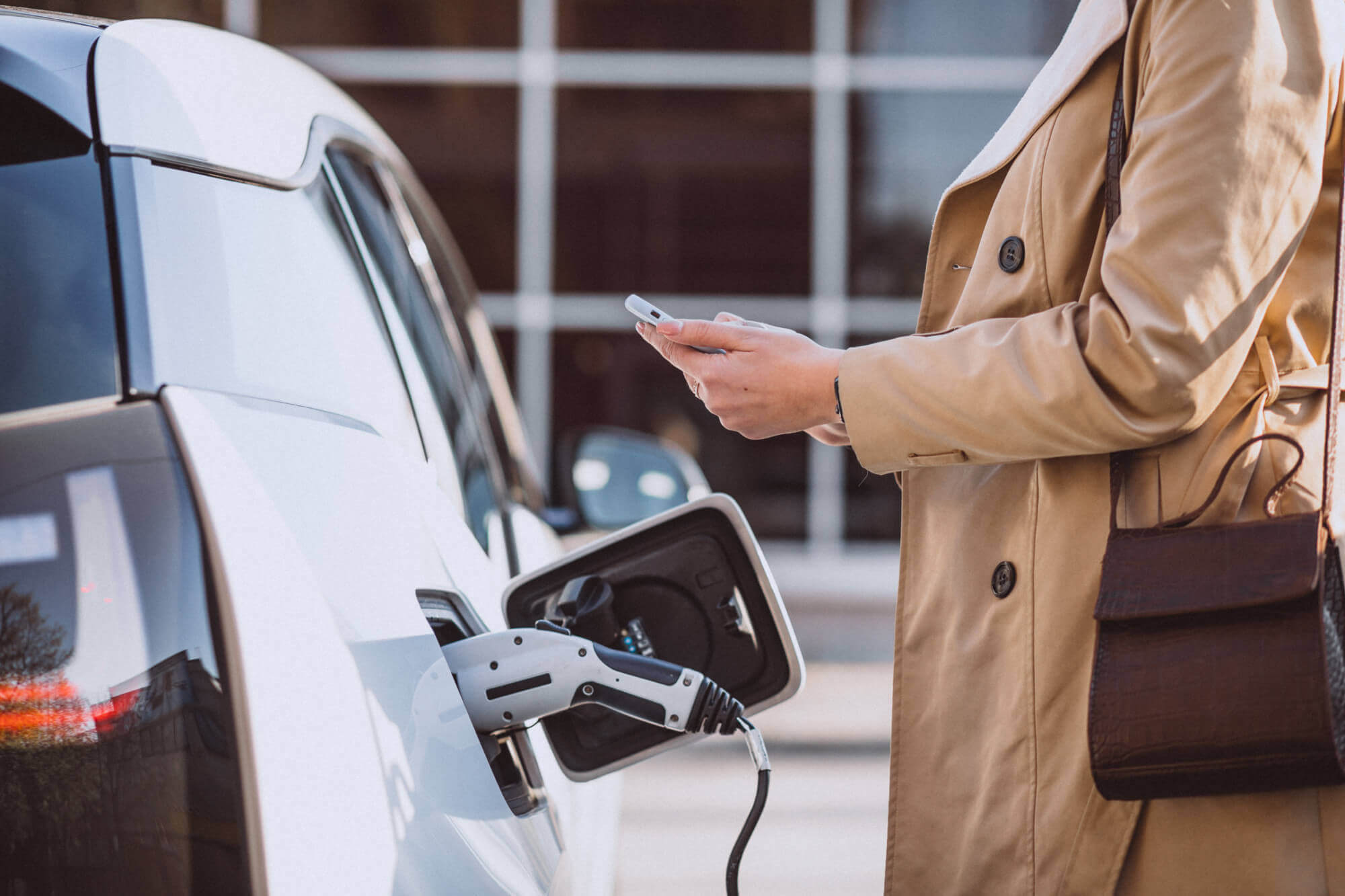 Una donna sta ricaricando la sua auto elettrica in una stazione di ricarica