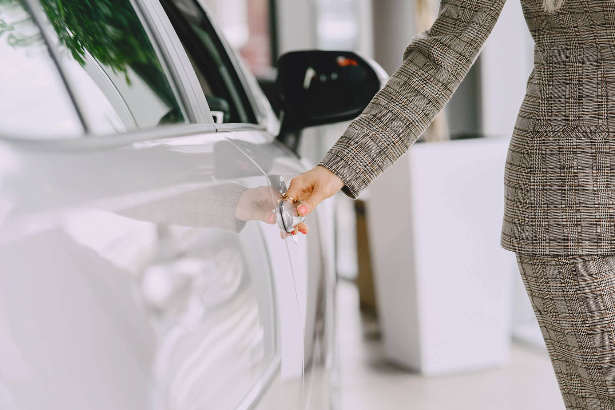 Una donna in giacca e pantaloni sta aprendo la portiera di un'auto